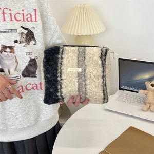 Detail van een pluizige gestreepte make-uptas van sherpa fleece met ritssluiting