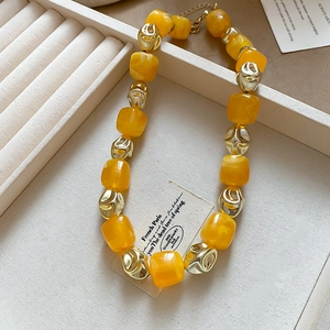 Detail of yellow acrylic beads and irregular gold metal links on a stylish bracelet