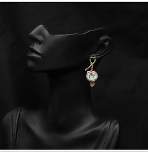 Detailed view of gold bow pearl earrings with heart pendant on model