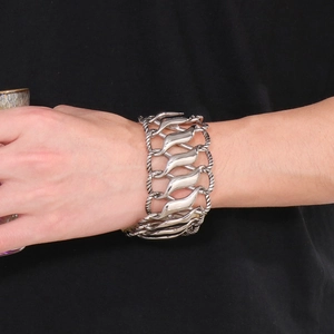Detail of silver twisted infinity symbol steel bracelet on male wrist against black background