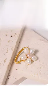 Macro detail of a golden flower ring crafted with five white and one purple pearl