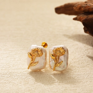 Macro detail of baroque pearl earrings with golden flower design and sunflower engraving
