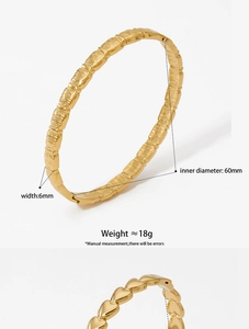 Detail view of gold stainless steel bangle with heart design and texture finish
