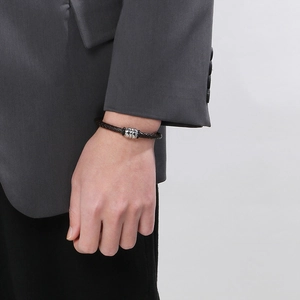 Close-up of a brown braided leather bracelet with a silver magnetic clasp on a wrist