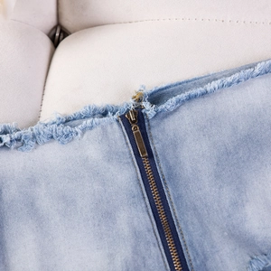 Detailaufnahme von hellblauen Denim-Shorts mit Metallreißverschluss und ausgefransten Kanten