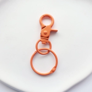 Close-up of bright orange painted metal lobster clasp hook and ring for bags and DIY crafts