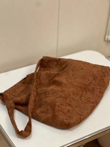 Close-up of brown suede tote bag with intricate paisley embroidery and vintage ethnic patterns