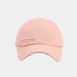 Detail of pink vintage cotton baseball cap with distressed holes and white embroidery