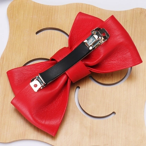Detailed close-up of a large red PU leather bow hair clip with sturdy metal fastening