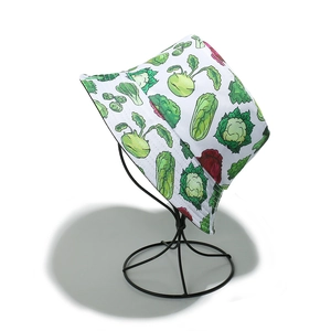 Detail of white cotton bucket hat with colorful vegetable print on a metal rack