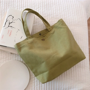 Close-up of grass green canvas tote bag with snap button and fabric texture details