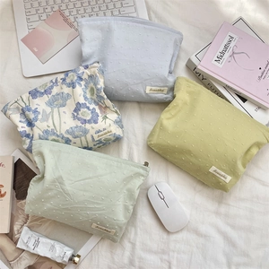 Macro shot of floral toiletry bags with zipper and brand label on a cozy white desk