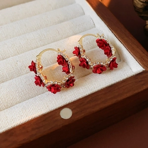 Detailed macro view of vintage red rose earrings with crystals on beige velvet jewelry box