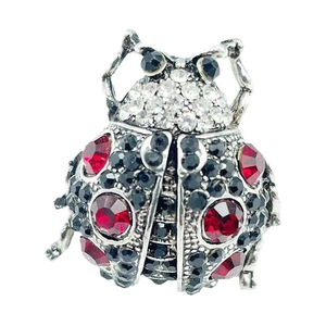 Close-up of a ladybug brooch with red, black, and white rhinestones on silver metal