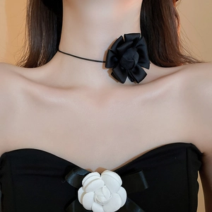 Detailed view of a black fabric flower choker paired with a white camellia corset top