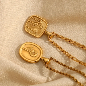 Détail de pendentifs en or 18 carats carrés et ovales avec gravures de tournesol