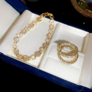 Gros plan d'un bracelet et de boucles d'oreilles dorés avec nacre et zircons pavés