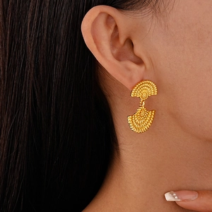 Macro view of gold fan-shaped geometric earrings with textured finish on model