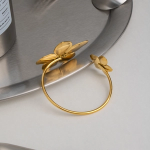 Dettaglio del bracciale rigido dorato in acciaio inossidabile con fiori 3D