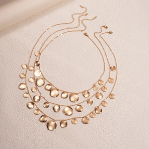 Detailed view of triple-layered golden necklace with textured circular metal pendants