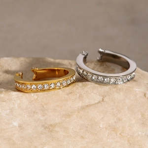 Detail of gold and silver rhinestone ear cuffs displayed on elegant natural stone