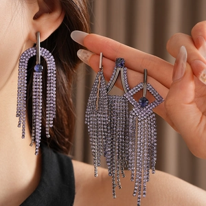 Macro shot of purple rhinestone tassel earrings with dark metal geometric hollow design