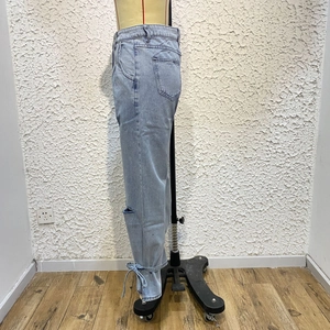 Detail view of light blue straight jeans with knee rip and drawstring hem on mannequin