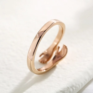 Detail of rose gold hugging hands open ring in stainless steel with elegant metallic luster