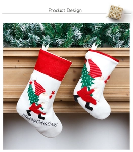 Detail of embroidered Christmas stockings hanging on a wooden mantel with pine needles