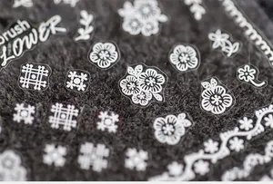 Macro detail of ultra-thin white floral nail stickers and lace patterns on dark fabric