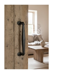 Close-up of vintage cast iron door handle with matte black texture on a rustic wooden door