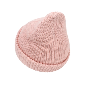 Close-up of pink knitted infant hat showing thick ribbed texture and rolled edge detail