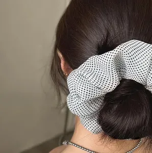 Polka dot mesh scrunchie shown in use with a ponytail hairstyle on a model