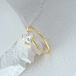 Macro detail of luxury gold ring featuring a brilliant round diamond in a four-prong setting