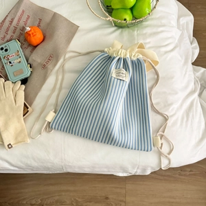 Detailaufnahme des blau-weiß gestreiften Kordelzugbeutels mit Lady Bug Etikett auf Bett
