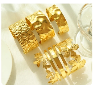 Detailed view of gold titanium bangles featuring hammered textures and cutout floral designs