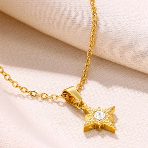Macro shot of gold star necklace with zircon pendant on elegant silk background