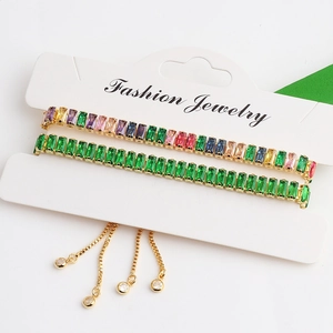 Close-up of adjustable gold-plated bracelets with green and rainbow baguette zircon stones