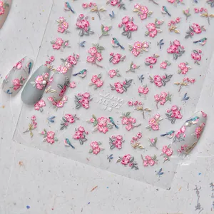 Macro shot of 5D embossed nail stickers featuring pink flowers and blue birds