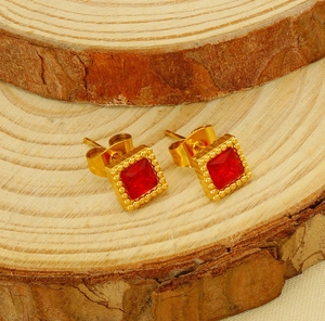 Detail of vintage square gold-plated stud earring with red zircon on natural wood