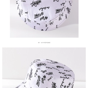 Detailed close-up of white cotton bucket hat with black street graffiti print and stitching