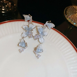 Close-up of butterfly earrings with light blue crystals and silver needles on ceramic plate