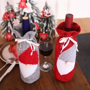 Detail of gray and red knitted gnome wine bottle covers on a festive wooden table