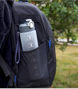 Gray gradient sports water bottle in a black backpack side pocket with nature background