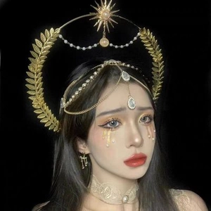 Detail view of golden sunburst crown headpiece with rhinestones and pearl dangles