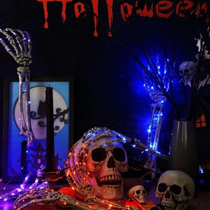 Blue and orange LED string lights wrapped around Halloween skulls and skeletal hands