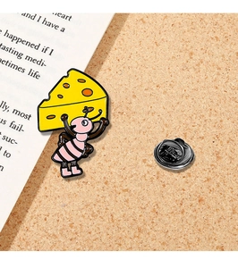 Detailed view of an ant holding cheese enamel pin on a cork board background
