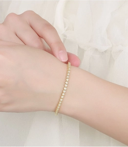 Close-up of a 2mm gold moissanite tennis bracelet worn on a woman's wrist