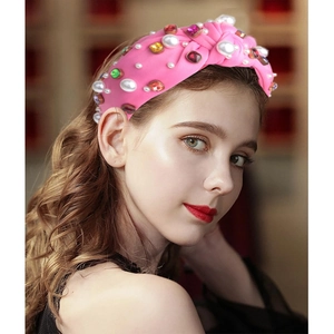 Pink fabric knotted headband with pearl and gemstone embellishments on model