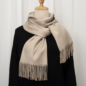 Detail of soft beige cashmere-feel scarf with long fringe tassels on a mannequin